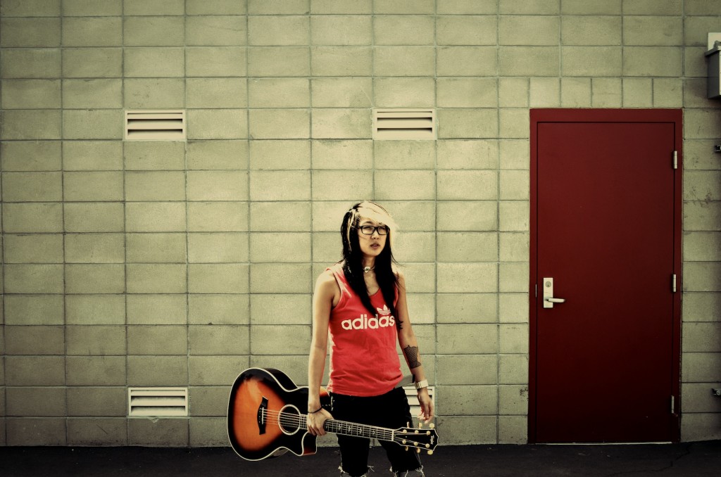 Christine Sako Gray Wall One Hand Holding Guitar